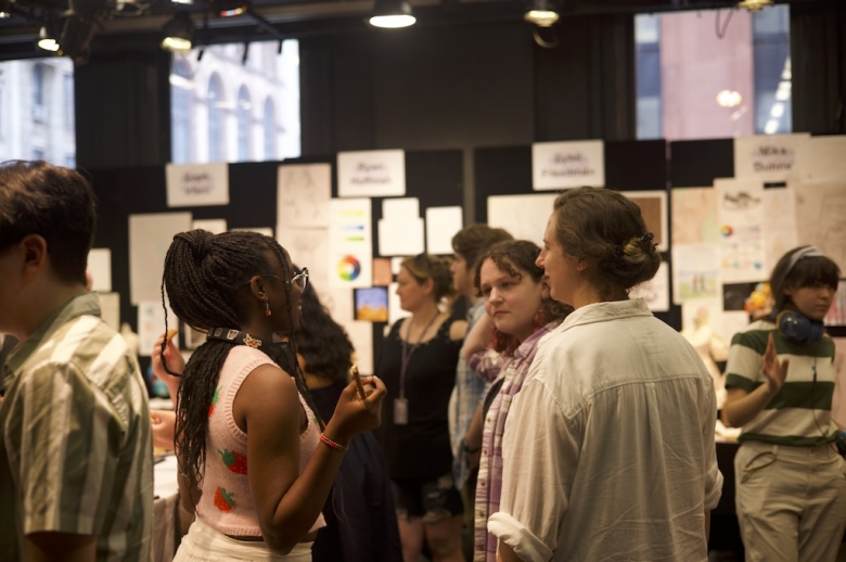 A group of Drama: Production & Design students and attendees stand and chat during the students' final project presentations.